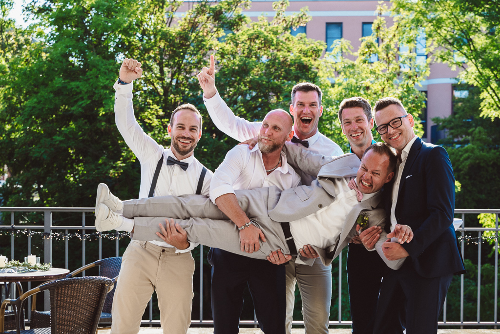 Gruppenfoto der Männer. 5 Männer tragen den Bräutigamund jubeln.