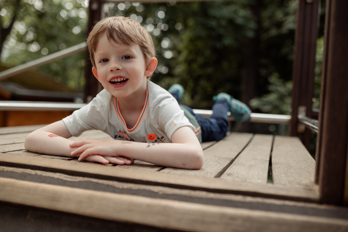 Junge liegend auf einem Spielplatz beim Fototag für natürliche Kindergartenfotos