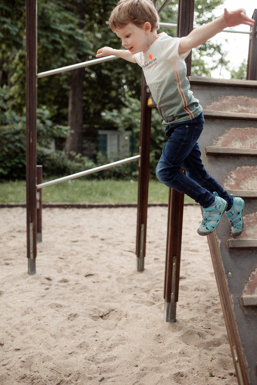 Kindergartenkind springt vom Klettergerüst beim Fototag für moderne Kitafotos