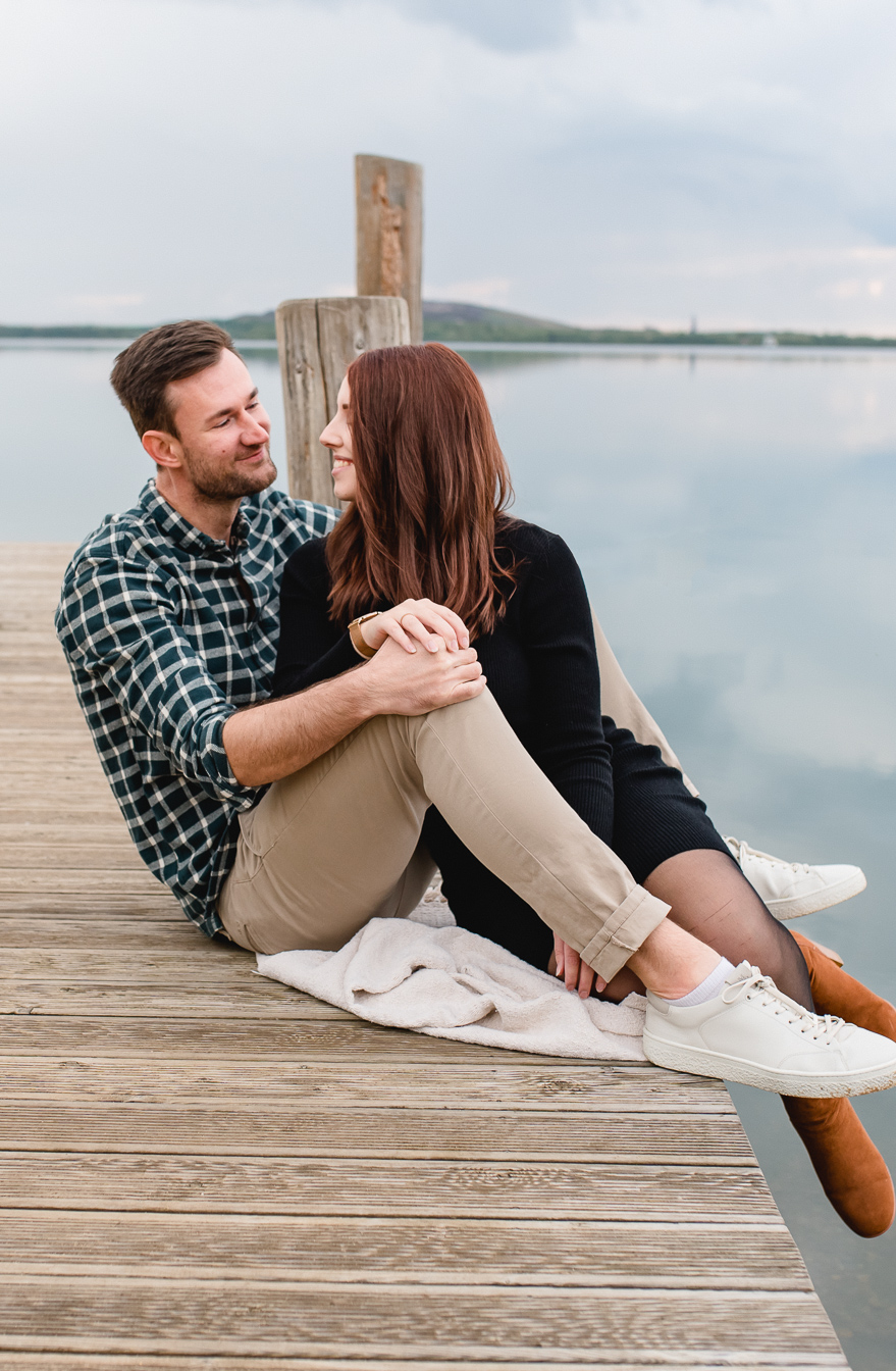Couple sitzt auf einem Steg und schaut isch in die Augen beim Paar Fotoshooting