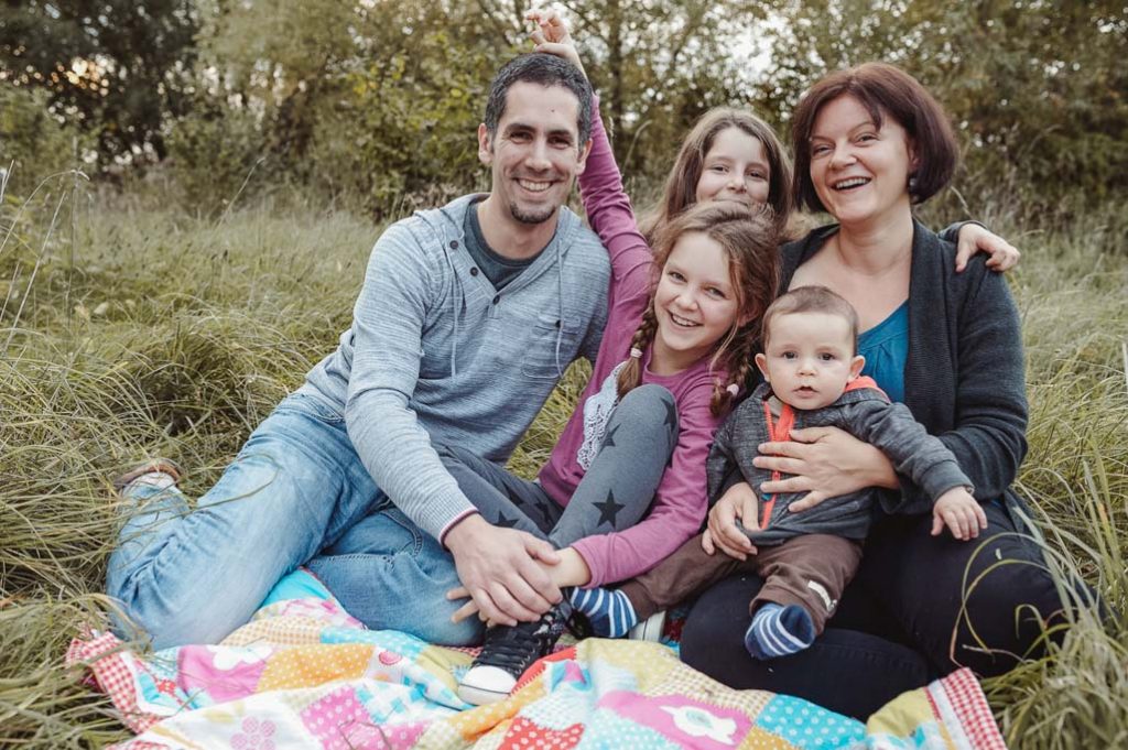 Foto vom Familienfotoshooting einer Fünfköpfigen Familie auf einer Decke im Park