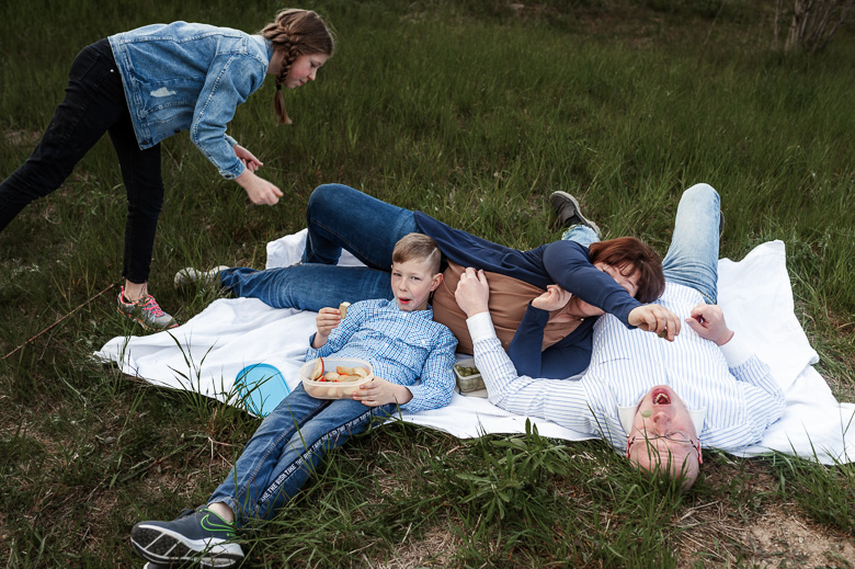 Familie liegt auf einer Decke im Gras für ungestellte Familienfotos in der Natur.