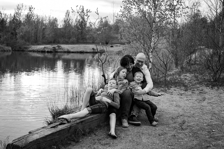 Fröhliche fünfköpfige Familie sitzt am See hintereinander beim Fotoshooting in Störmthal, Schwarzweißbild