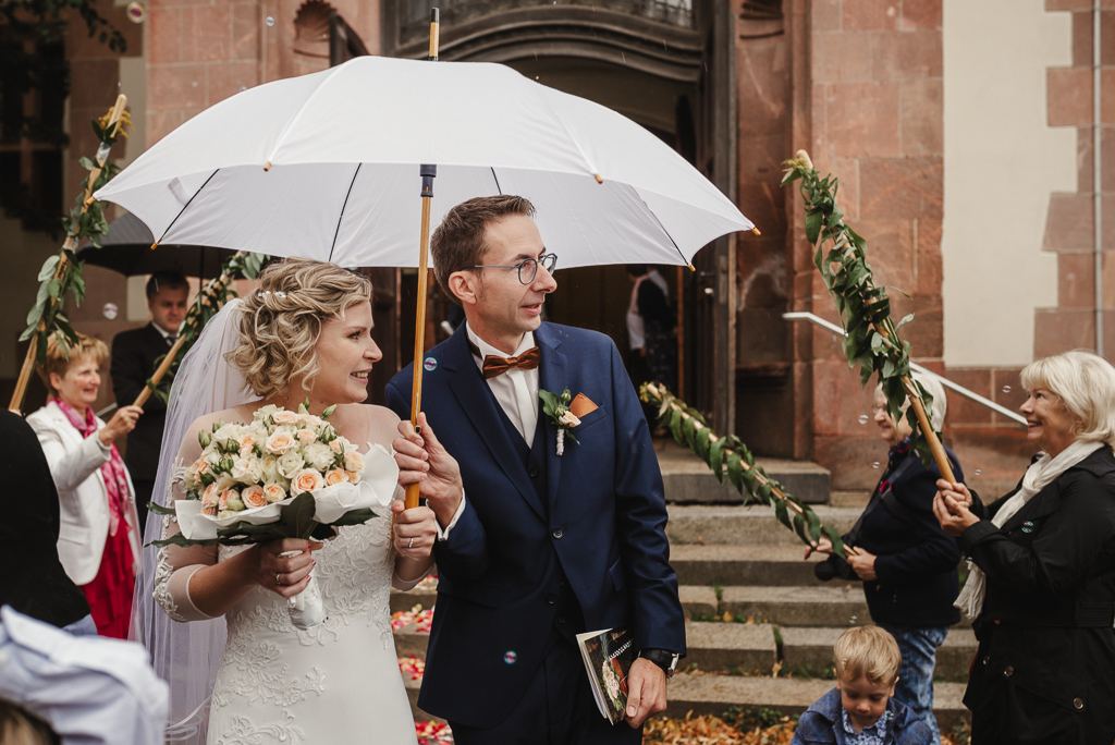 Brautpaar mit Regenschirm vor der Kirche